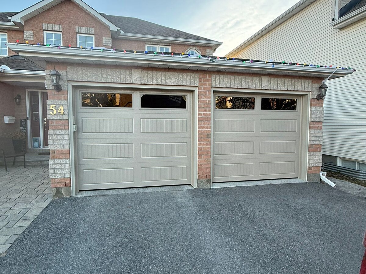 Two white single garage doors on a two-tone brick home