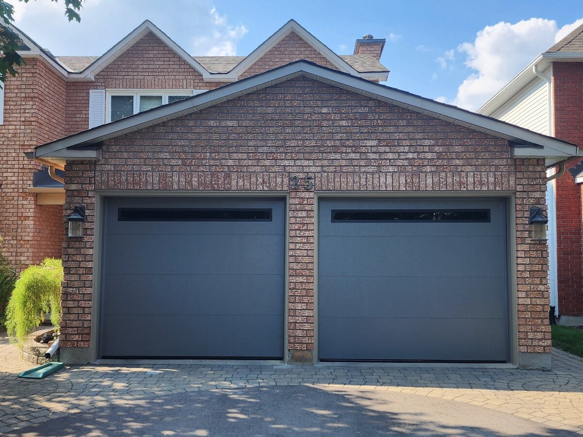 Two charcoal grey garage doors on a brick home
