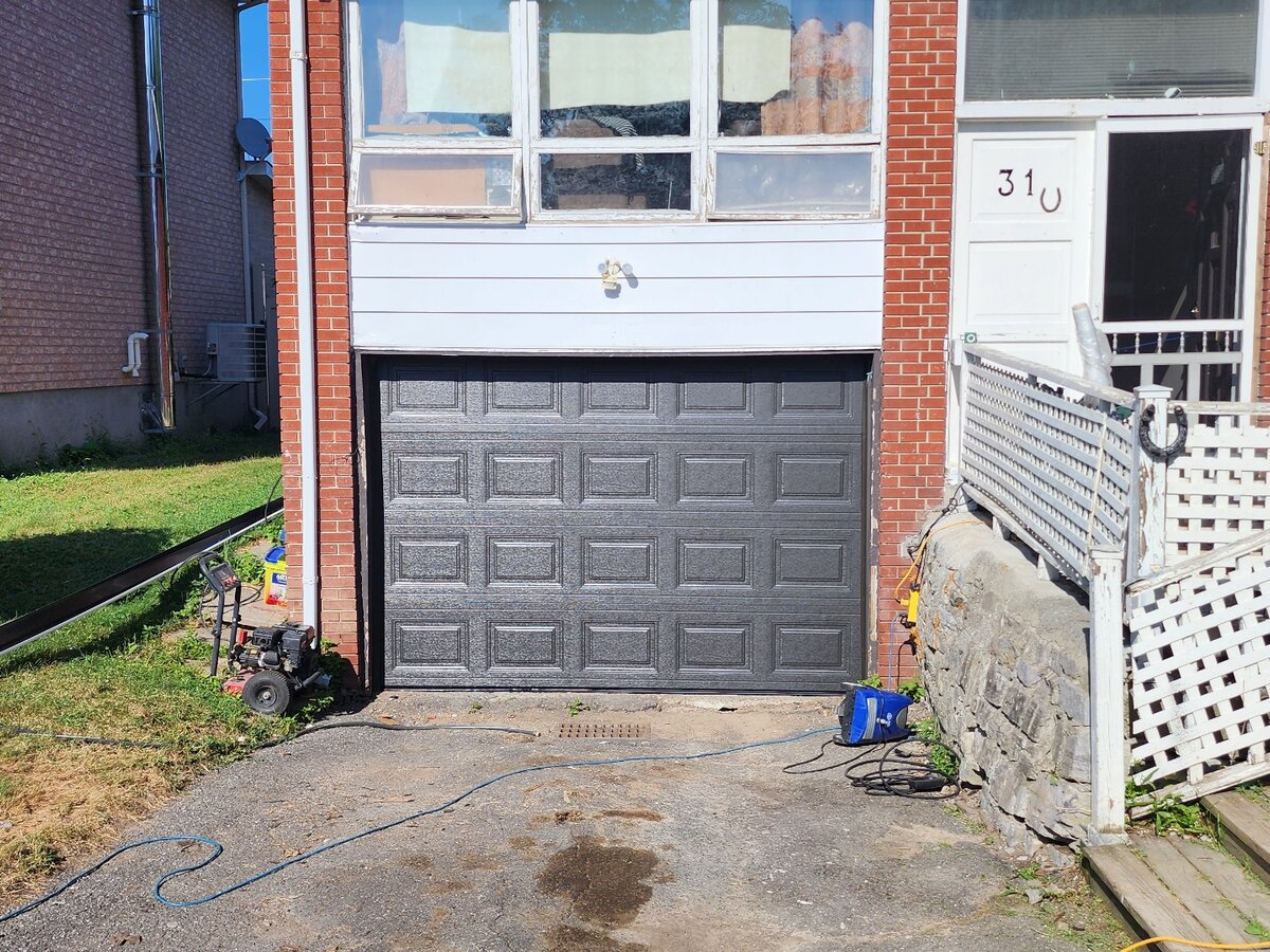 Dark brown raised-panel single garage door on a brick home