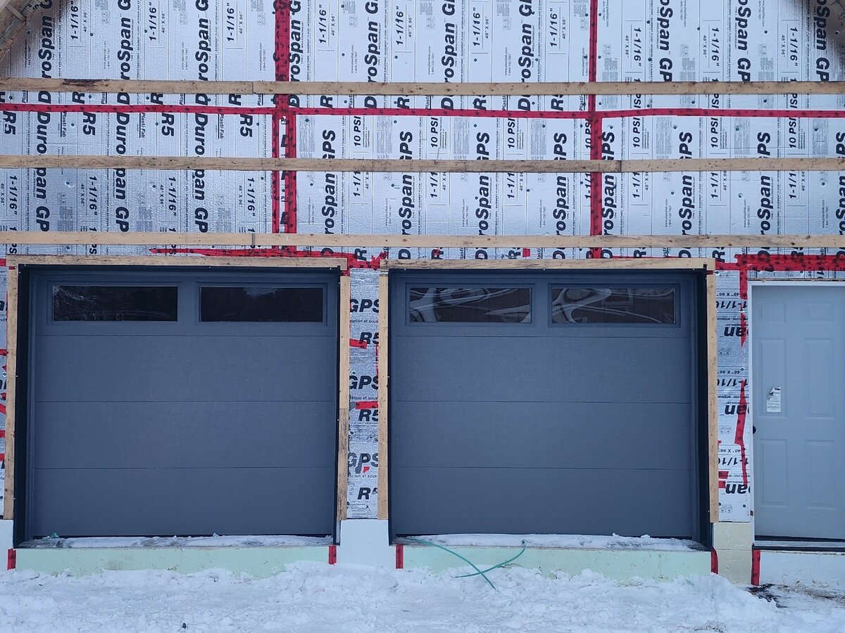 Two black modern garage doors on a new-construction detached garage
