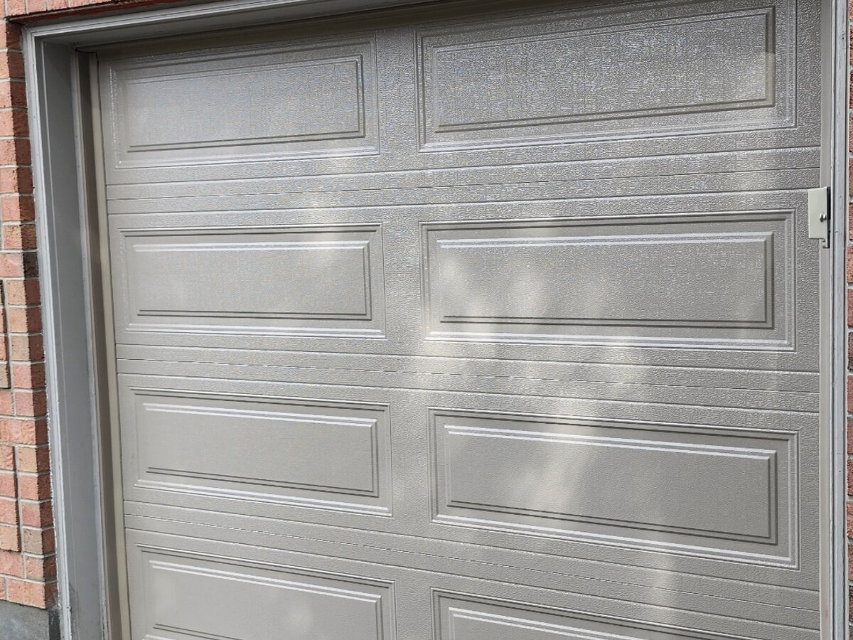Tan raised-panel single garage door on a home