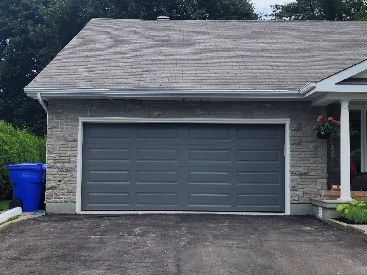 Grey raised-panel double garage door on a brick bungalow