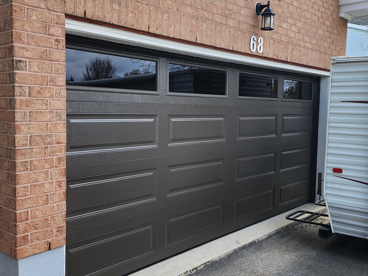 Black long-panel double garage door on a brick home