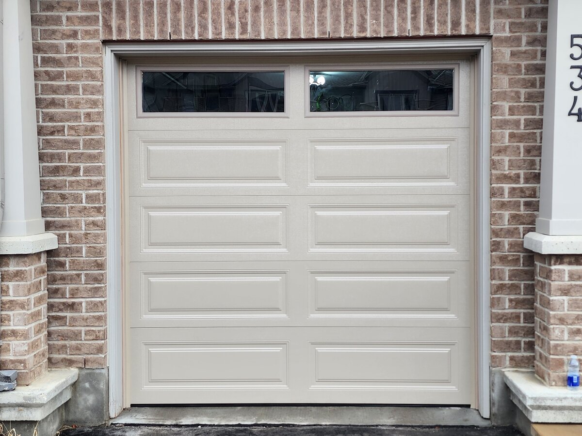 Almond single garage door with a top window row on a brick home