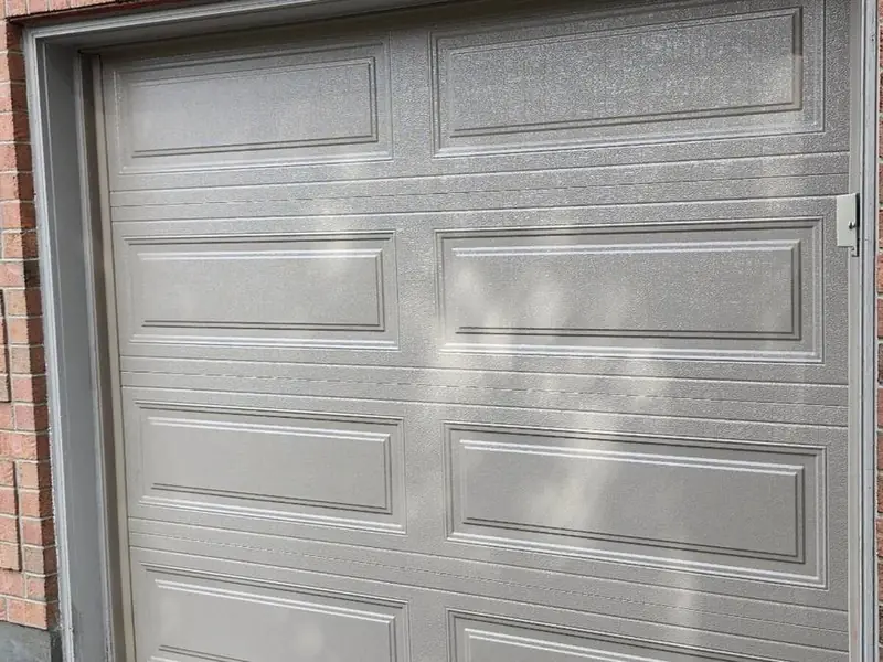 Tan raised-panel single garage door on a home