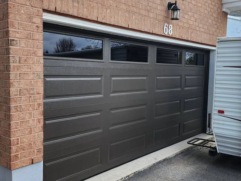 Black long-panel double garage door on a brick home