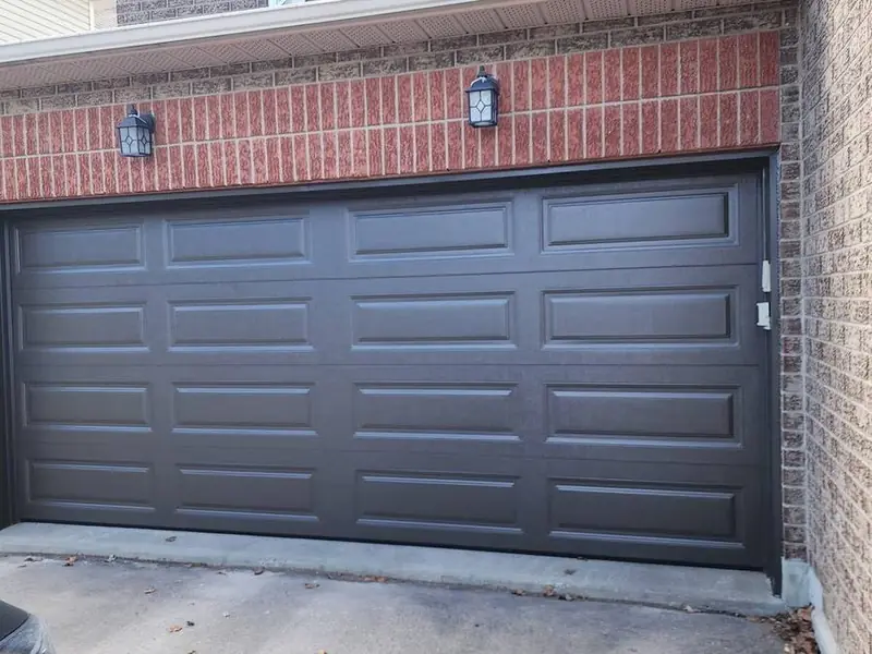Charcoal grey raised-panel double garage door on a two-tone brick home
