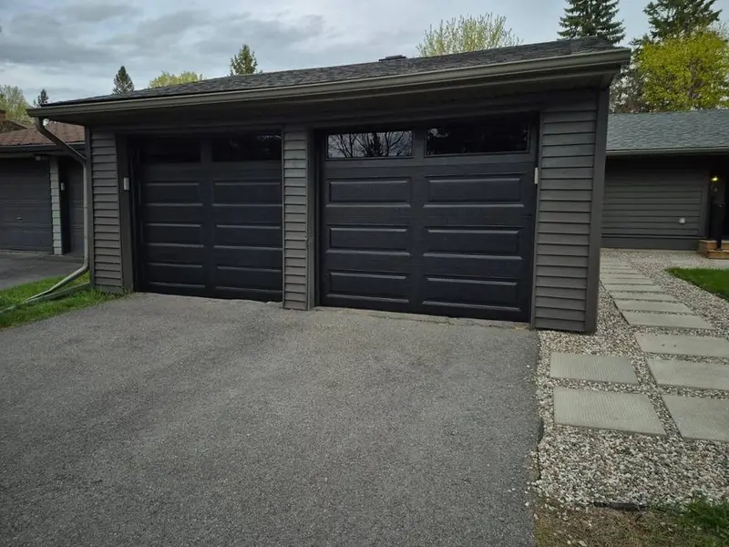 Black modern double garage door on a detached garage with a long driveway