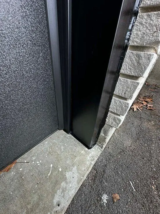 DPS Garage Doors dark aluminum capping finished around a garage door jamb against stone in Ottawa