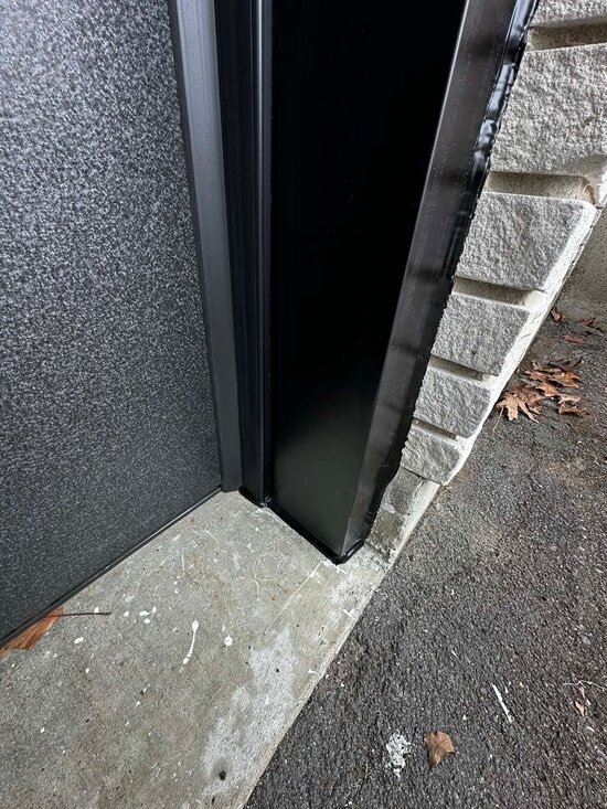 DPS Garage Doors dark aluminum capping finished around a garage door jamb against stone in Ottawa