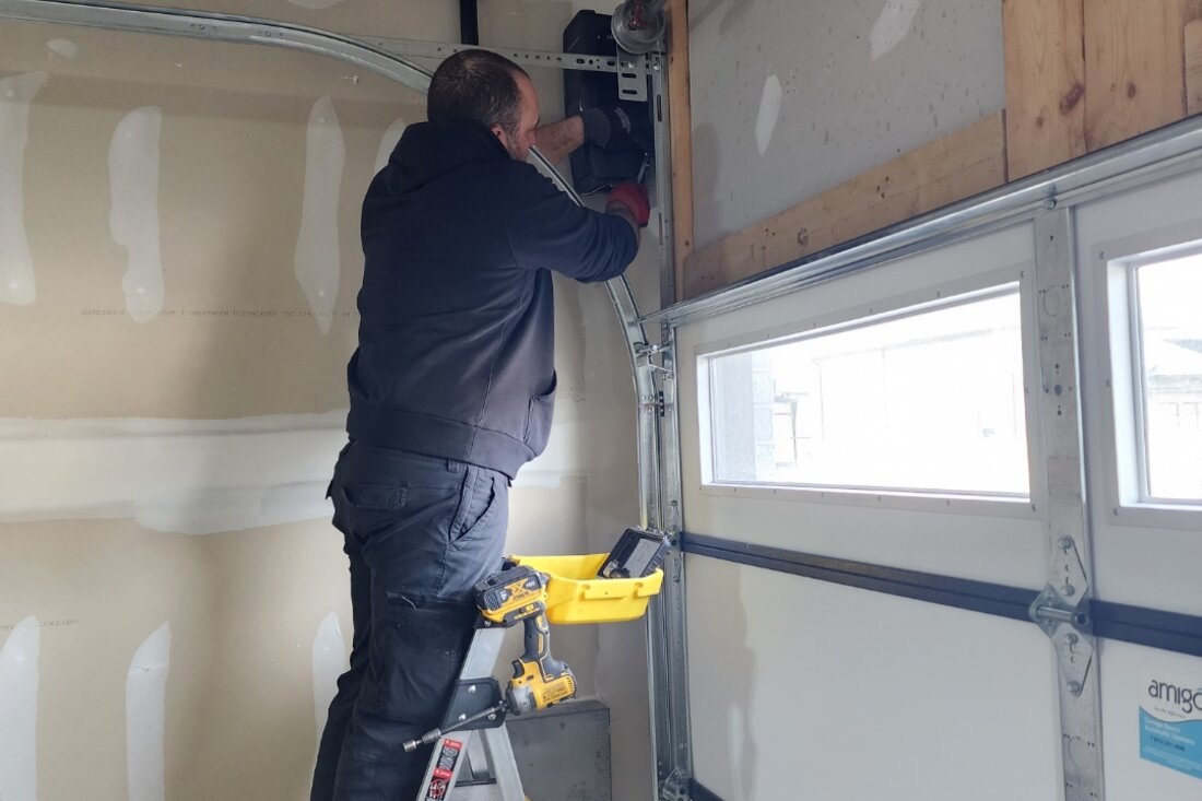 DPS Garage Doors technician repairing a garage door track and opener in Ottawa